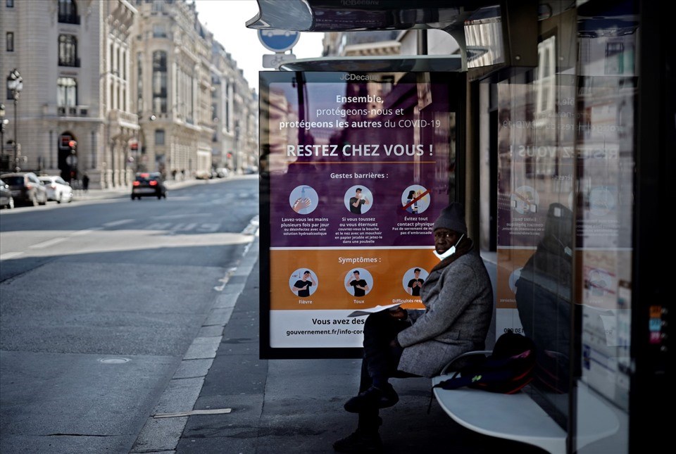Một người đàn ông ngồi ở trạm xe buýt có tấm áp phích ghi "Hãy ở nhà" trên đường phố Paris ngày 1.4.2020. Ảnh: AFP Một người đàn ông ngồi ở trạm xe buýt có tấm áp phích ghi "Hãy ở nhà" trên đường phố Paris ngày 1.4.2020. Ảnh: AFP