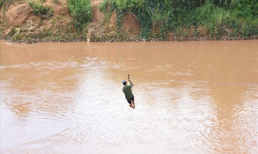 Người dân huyện Ngọc Hồi, tỉnh Kon Tum đu dây qua sông giữa dòng nước lũ chảy xiết. Ảnh T.T