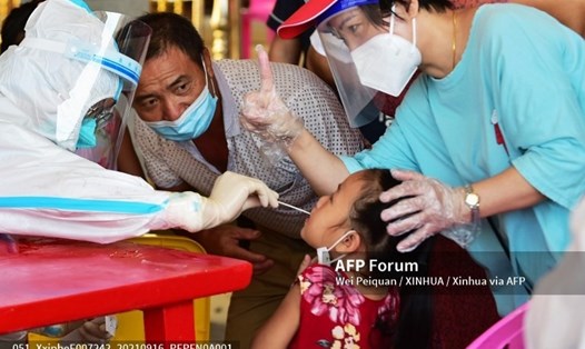 Nhân viên y tế lấy mẫu xét nghiệm cho một bé gái ở Phủ Điền, tỉnh Phúc Kiến, Trung Quốc. Ảnh chụp ngày 16.9.2021 của AFP