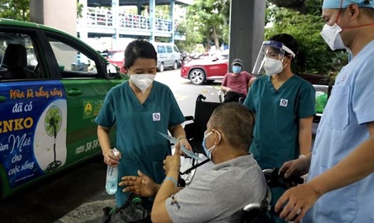 Nhân viên y tế Bệnh viện Nhân dân Gia Định đưa anh C ra xe chở về nhà. Ảnh: BVCC
