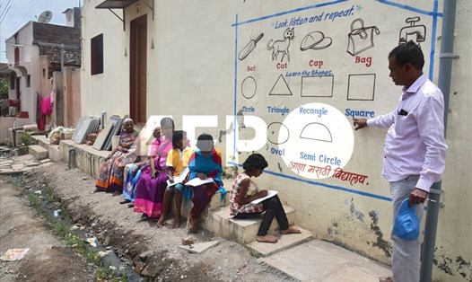 Kalidas Chavdekar, giáo viên trường Aasha Marathi Vidyalay viết lên tường của một ngôi nhà để dạy những học sinh không có điện thoại  thông minh để học trực tuyến ở Solapur, thuộc bang Maharashtra, Ấn Độ vào tháng 8.2020. Ảnh minh họa. Ảnh: AFP