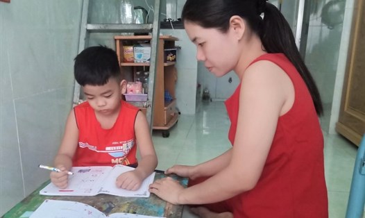 Chị Nguyễn Thị Thu Hương đang tranh thủ hướng dẫn con nhỏ học bài. Ảnh: Đức Long