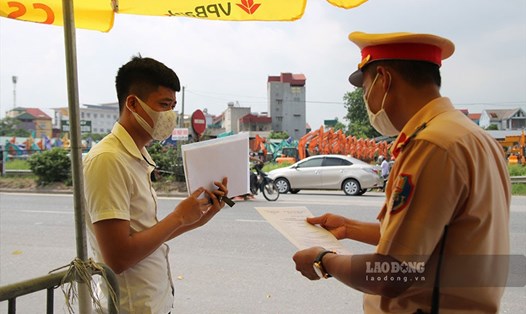 Cảnh sát giao thông kiểm tra giấy tờ người dân di chuyển vào thành phố Hà Nội tại Quốc lộ 5. Ảnh T.Vương