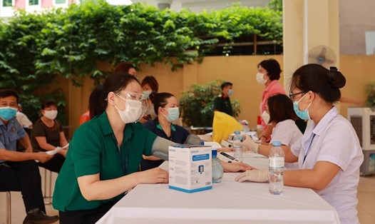 Cán bộ y tế khám sàng lọc trước khi tiêm vaccine COVID-19 tại Hà Nội. Ảnh: Lao Động