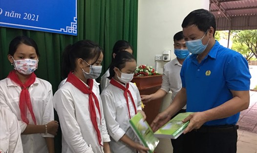 Phó Chủ tịch Thường trực LĐLĐ tỉnh Nguyễn Kỳ Sơn trao tặng vở cho học sinh. Ảnh: TT