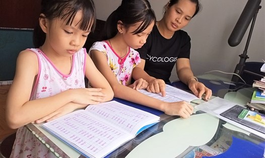 Chị Nguyễn Thị Ánh Tuyết (CN Công ty Nissei Electric Việt Nam, TPHCM) tranh thủ dạy con học theo cách truyền thống. Ảnh: Đức Long