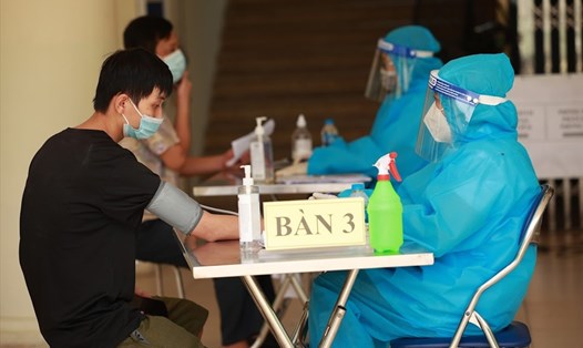 Cán bộ y tế khám sức khỏe trước khi tiêm chủng vaccine COVID-19 tại một điểm tiêm ở Hà Nội. Ảnh: Hải Nguyễn