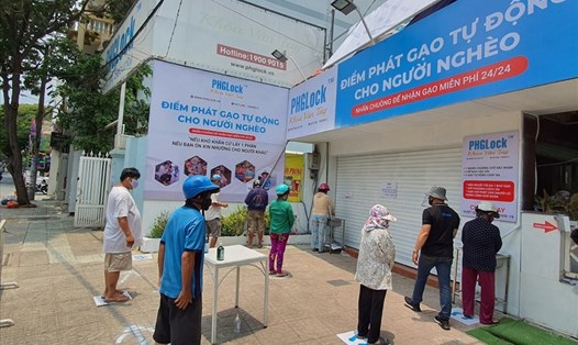 Người dân xếp hàng chờ lấy gạo miễn phí tại “ATM gạo” quận Tân Phú. Ảnh: Trí Minh