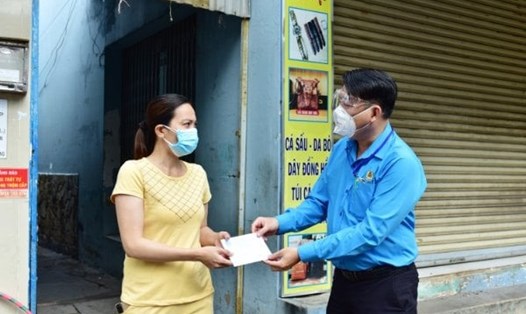 Chủ tịch LĐLĐ quận Bình Tân (TPHCM) Nguyễn Văn Hải trao tiền hỗ trợ cho gia đình CNLĐ bị mất vì COVID-19 theo quy định của Tổng LĐLĐVN. Ảnh: Đức Long
