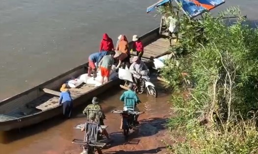 Đò chở hàng lậu từ phía Lào cập bờ ở khóm Tân Kim (thị trấn Lao Bảo, huyện Hướng Hóa, tỉnh Quảng Trị) rồi được người dân vận chuyển hàng lên bờ bằng xe môtô vào 8h ngày 18.8. Ảnh: Nhóm PV.