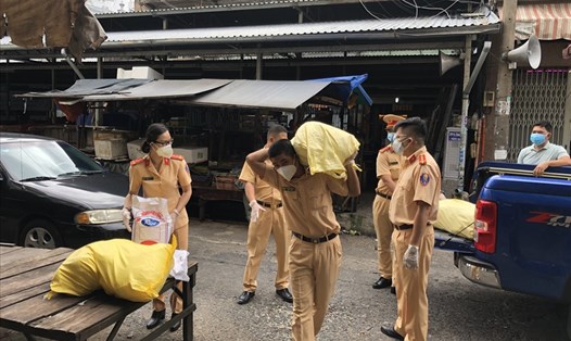 Cán bộ, chiến sĩ Đội CSGT Chợ Lớn mang các phần gạo đến hỗ trợ người dân. Ảnh: CACC