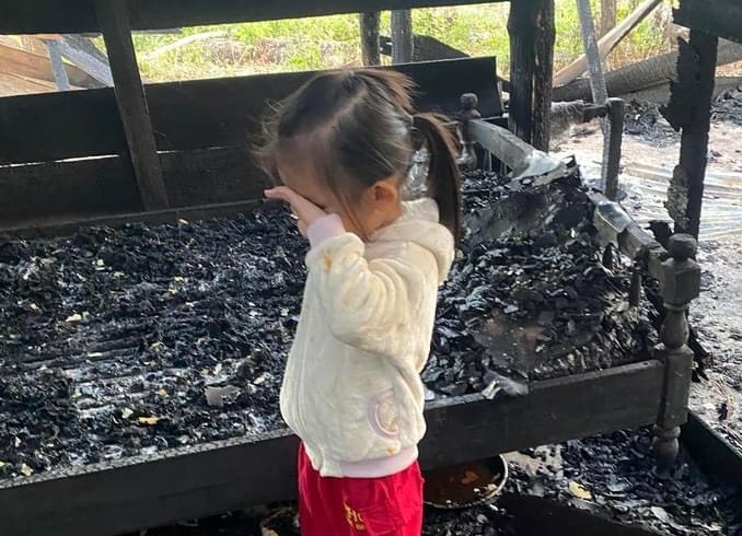 Em bé 5 tuổi buồn bã khi ngôi nhà che mưa, che nắng bị ngọn lửa thiêu rụi. Ảnh: Xuân  Ánh
