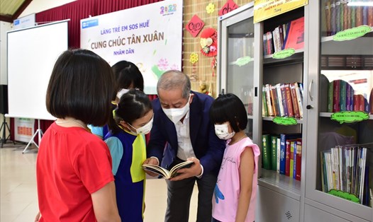Phó Bí thư Thường trực Tỉnh uỷ Phan Ngọc Thọ giới thiệu sách cho trẻ ở làng SOS. Ảnh: PV.