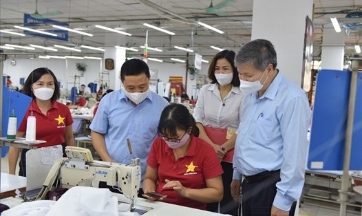 Giám đốc BHXH Thành phố Nguyễn Đức Hòa (bên phải ảnh) hỏi thăm công nhân tại phân xưởng may thuộc Tổng Công ty May 10.  Ảnh: BHHN