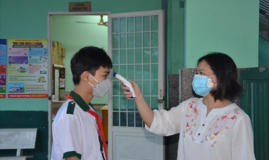 Học sinh được kiểm tra thân nhiệt trước khi vào trường học. Ảnh: Huyên Nguyễn