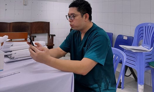 Sau giờ khám bệnh tại khu thu dung, bác sĩ Trần Tiến Đạt tiếp tục tư vấn hướng dẫn online cho bệnh nhân COVID-19 tập thở. Ảnh: PV