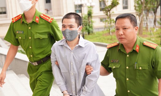 Nguyễn Trung Huyên (giữa) - kẻ đóng 10 chiếc đinh vào đầu bé gái 3 tuổi bị dẫn giải vào phòng xử án. Ảnh: V.D