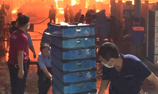 Công nhân người lao động cứu hàng hoá ra khỏi đám cháy, số đông công nhân khác đang hỗ trợ dập tắt đám cháy. Ảnh: CTV
