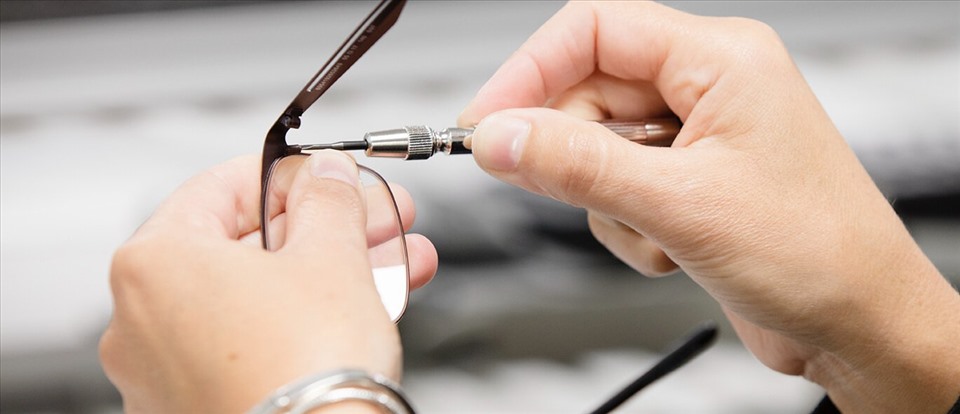 Dùng tua vít vặn chặt ốc vít để giúp kính đeo mắt được chắc chắn hơn. Ảnh: Xinhua