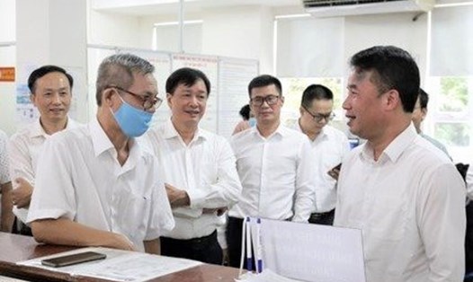 Tổng Giám đốc BHXH Việt Nam Nguyễn Thế Mạnh (bên phải) trao đổi với người dân đến làm thủ tục thông qua tiện ích đặt lịch làm việc với cơ quan BHXH
