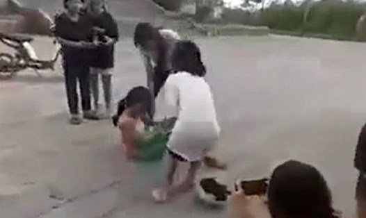 2 nữ sinh đánh rồi lột áo bạn, các bạn khác vây quanh quay clip và cười đùa. Ảnh cắt từ video.