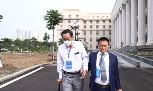 Cựu Thứ trưởng Y tế Cao Minh Quang (áo trắng) chống nạng đến toà. Ảnh: Việt Dũng