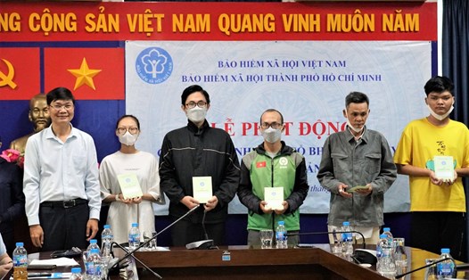 Ông Nguyễn Quốc Thanh - Phó Giám đốc, phụ trách BHXH TPHCM (bìa trái) - trao đại diện sổ BHXH cho người dân có hoàn cảnh khó khăn. Ảnh: Đức Long