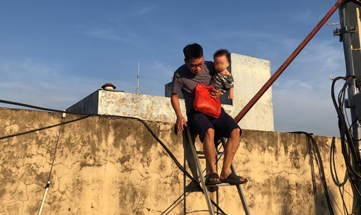 Anh Nguyễn Kế Hoà bế con trèo sang tòa nhà bên cạnh để đi nhờ thang máy xuống sân (ảnh chụp chiều 2.11). Ảnh: Hạnh Hân