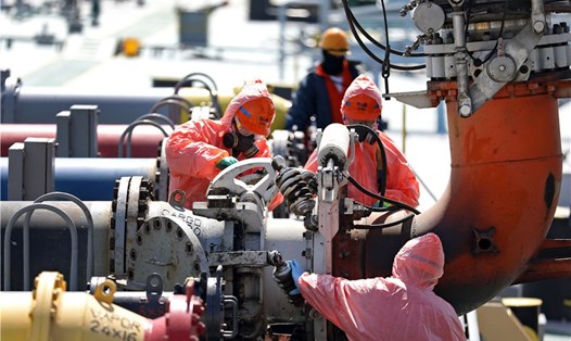 Công nhân nối đường ống lên tàu chở dầu tại cảng ở Đại Liên, tỉnh Liêu Ninh, Trung Quốc. Ảnh: Xinhua