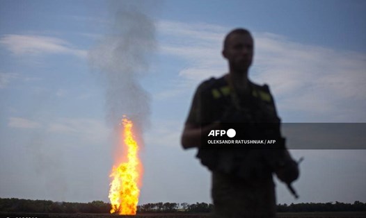 Một quân nhân Ukraina đứng gác khi ngọn lửa bùng lên ở phía xa từ một đường ống dẫn khí đốt đã bị hư hại do pháo kích ở vùng Donetsk năm 2015. Ảnh: AFP