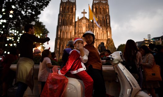 Một người mẹ đưa con đi chơi Giáng sinh tại Hà Nội. Ảnh: AFP