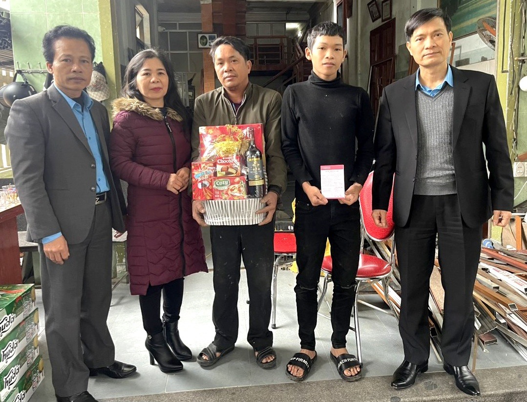 Ông Võ Văn Tiến - Phó Chủ tịch LĐLĐ tỉnh Quảng Bình (đầu tiên, từ phải sang) - trao sổ tiết kiệm cho cháu Trần Anh Quốc. Ảnh: Đ.T