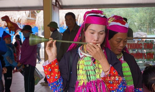 Phụ nữ người dao thử kèn lá tại phiên chợ vùng cao Hà Lâu. Ảnh: Đoàn Hưng