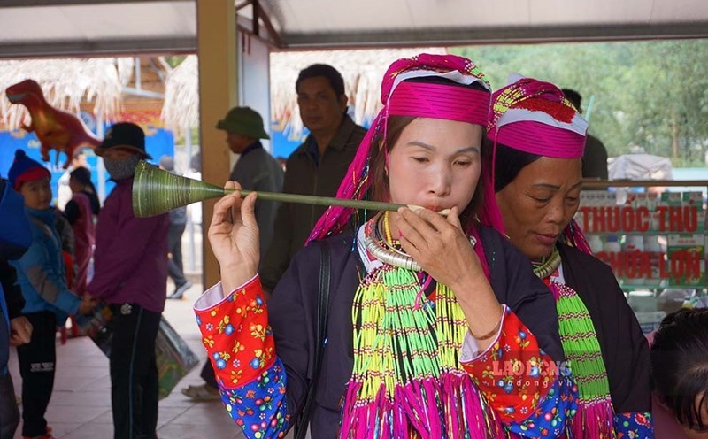 Phụ nữ người dao thử kèn lá tại phiên chợ vùng cao Hà Lâu. Ảnh: Đoàn Hưng