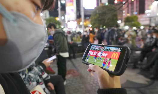 Một cổ động viên Nhật Bản xem trận đấu của đội nhà trên điện thoại di động. Ảnh: Kyodo