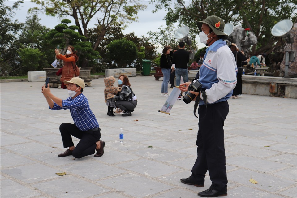 Ông Ánh  bất lực nhìn du khách chụp hình tại chùa Linh Ứng Bãi Bụt (Đà Nẵng) bằng điện thoại thông minh thay vì sử dụng dịch vụ chụp hình lấy liền của ông. Ảnh: Nguyễn Linh