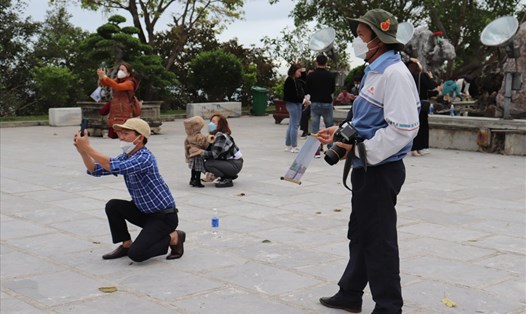 Ông Ánh  bất lực nhìn du khách chụp hình tại chùa Linh Ứng Bãi Bụt (Đà Nẵng) bằng điện thoại thông minh thay vì sử dụng dịch vụ chụp hình lấy liền của ông. Ảnh: Nguyễn Linh