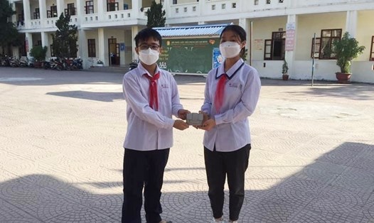 Em Phạm Minh Tuấn (học sinh THCS Tràng Cát) trao trả chiếc ví cho người đánh mất. Ảnh: Trường THCS Tràng Cát