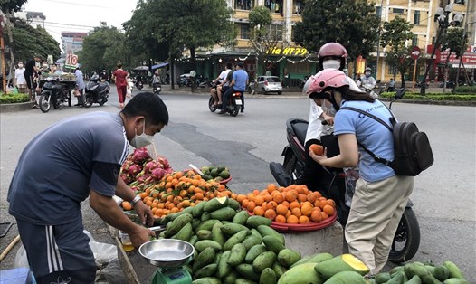 Công nhân mua hoa quả tại cổng chợ Mun (xã Kim Chung, huyện Đông Anh, Hà Nội) sau giờ làm. Ảnh: Quế Chi
