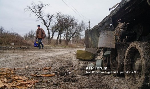 Người dân đi ngang qua một chiếc xe tăng bị hư hỏng của quân đội Ukraina. Ảnh: AFP