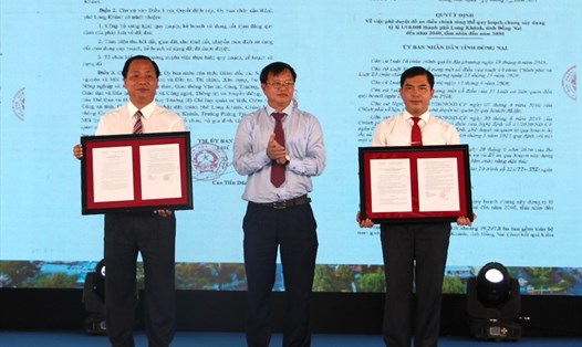 Chủ tịch UBND tỉnh Đồng Nai Cao Tiến Dũng (ở giữa) trao quyết định phê duyệt đồ án điều chỉnh quy hoạch chung, quy hoạch sử dụng đất và tặng hoa cho thành phố Long Khánh. Ảnh: Hà Anh Chiến