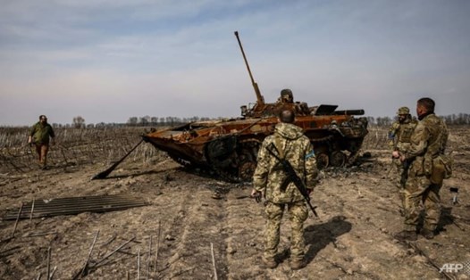 Binh sĩ Ukraina đứng bên một chiếc xe tăng Nga bị cháy ở ngoại ô Kiev ngày 31.3. Ảnh: AFP