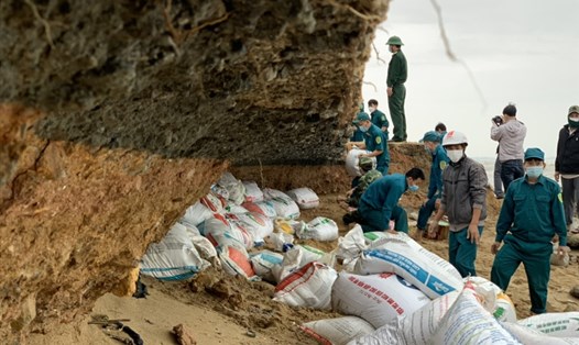 Lực lượng chức năng cùng người dân thôn Phổ Trường dùng bao dồn cát vào để chắn tạm thời sóng biển. Ảnh: Thanh Chung