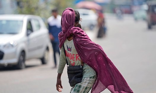 Một người trùm kín đầu đi dưới trời nắng ở Ấn Độ. Ảnh: AP