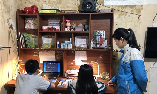 Nữ công nhân hướng dẫn con học online trong căn phòng trọ thuộc xã Kim Chung, huyện Đông Anh, Hà Nội. Ảnh: Bảo Hân
