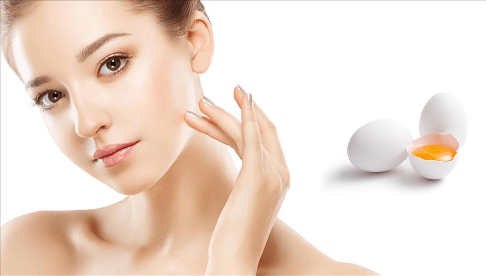 Người phụ nữ chạm nhẹ v&agrave;o mặt, b&ecirc;n cạnh l&agrave; hai quả trứng, một quả đ&atilde; được đập vỡ để lộ l&ograve;ng đỏ.