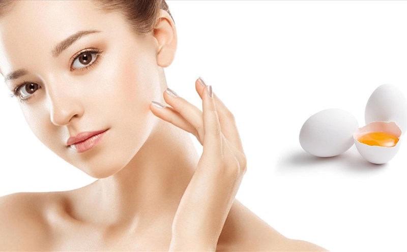 Trứng Gà Công Nghiệp Bao Nhiêu Calo? Dinh Dưỡng Và Lợi Ích 4 Người phụ nữ chạm nhẹ vào mặt, bên cạnh là hai quả trứng, một quả đã được đập vỡ để lộ lòng đỏ.