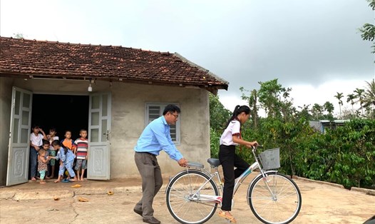 Thầy Mai Văn Chuyền thay mặt nhà hảo tâm tặng xe đạp và hướng dẫn các em học sinh nghèo sử dụng. Ảnh: Trung Dũng