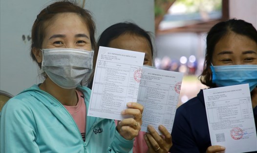 Nữ công nhân Trần Thị Mến (bìa trái ảnh) cùng các công nhân cười tươi khi được cầm tờ rời BHXH trên tay. Ảnh: Hưng Thơ.