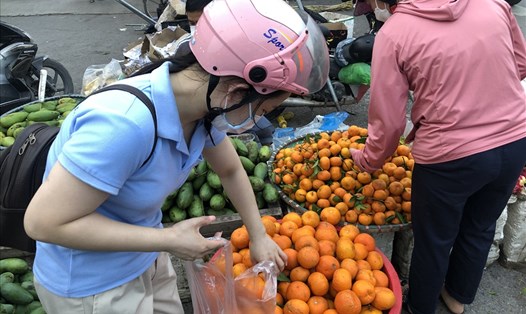 Nữ công nhân KCN Thăng Long (Hà Nội) mua hoa quả trên đường đi làm về. 
Ảnh: Bảo Hân